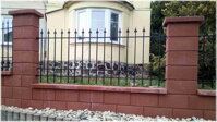 černý kovaný plot instalovaný mezi zděnými sloupky
